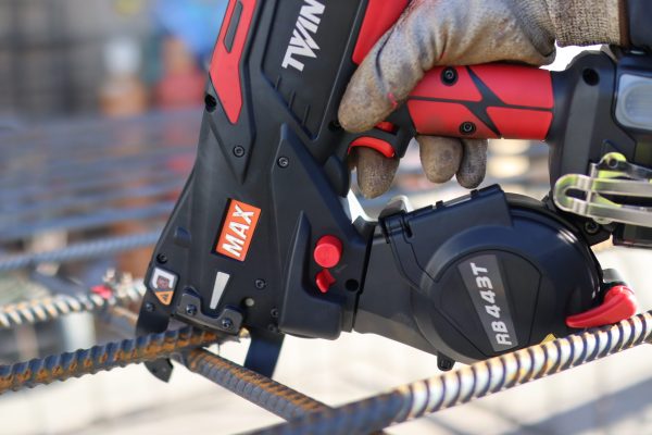 A worker with gloved hand using the Max TwinTier RB443T Rebar Tying tool to tie rebar up close.