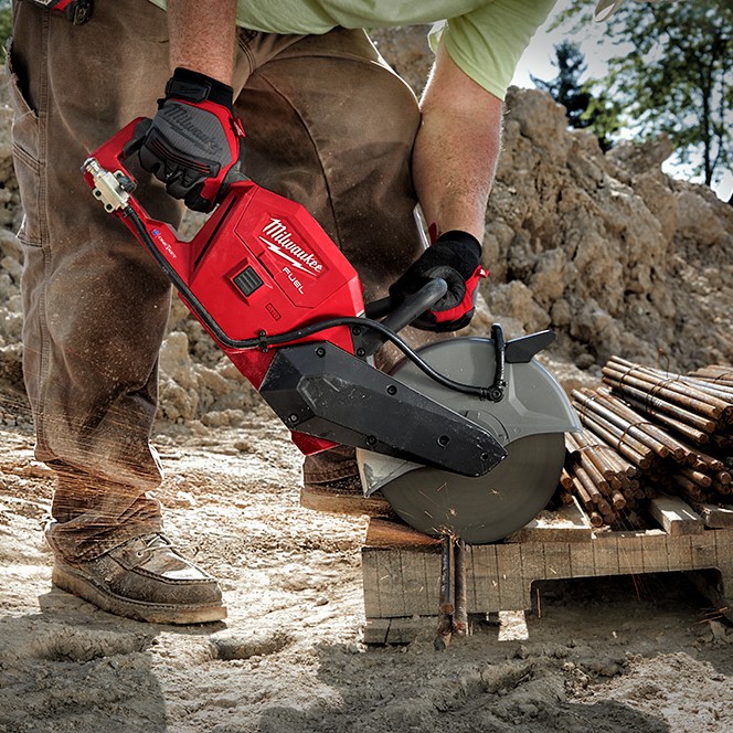 Milwaukee M18 FUEL 9-inch cordless cut-off saw cutting bundled rebar on an outdoor jobsite, shown in use by a worker wearing gloves, with abrasive cutting blade engaged and sparks visible during dry cutting