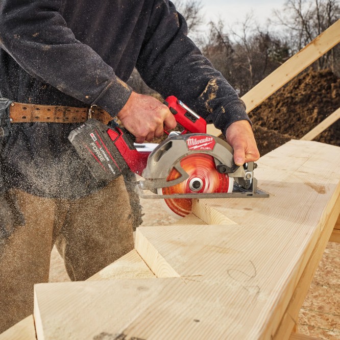 Milwaukee M18 FUEL 7-1/4 inch circular saw cutting stair stringer lumber on jobsite, sawdust visible during cut