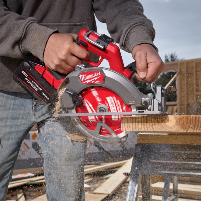 Milwaukee M18 FUEL 7-1/4 inch circular saw making bevel cut on dimensional lumber with FORGE HD12.0 battery installed, sawdust visible during cut