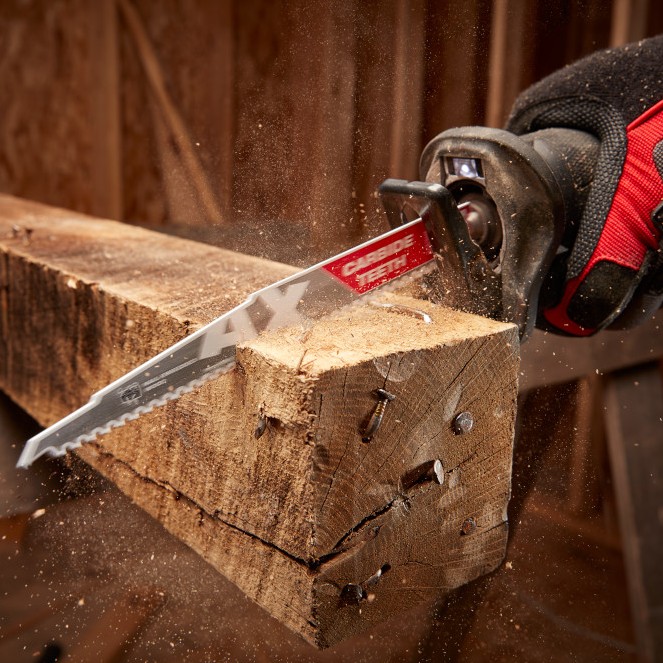 Milwaukee SAWZALL reciprocating saw cutting through a wood beam with embedded nails using an AX carbide tooth demolition blade with wood dust flying during the cut