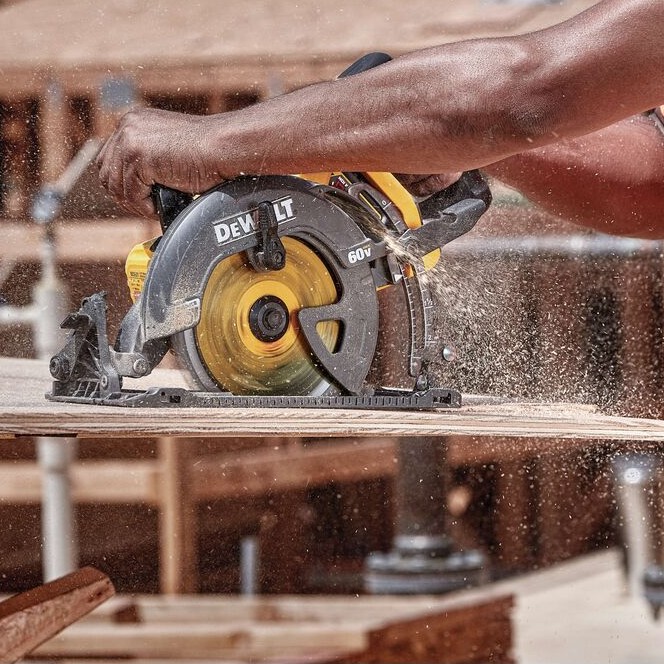 DEWALT FLEXVOLT 60V MAX 7-1/4″ rear handle worm drive style circular saw cutting plywood with sawdust visible, operator hands on rear and front handles, construction framing background