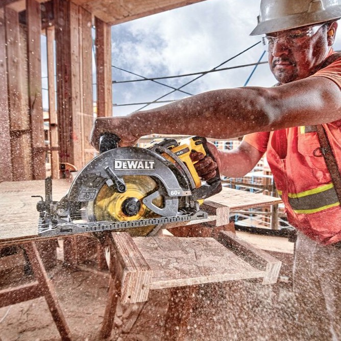 DEWALT FLEXVOLT 60V MAX rear handle worm drive style circular saw cutting engineered wood I-joist, worker wearing hard hat and safety glasses, heavy sawdust visible
