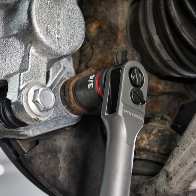 Milwaukee INSIDER box ratchet head with pass-through socket installed on automotive suspension bolt, close-up showing low-profile access in tight engine bay area