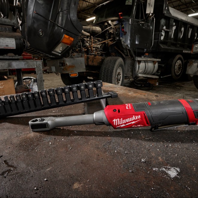 Milwaukee M12 FUEL INSIDER extended reach box ratchet on workbench with metric box ratchet sockets set, heavy truck in background showing shop environment