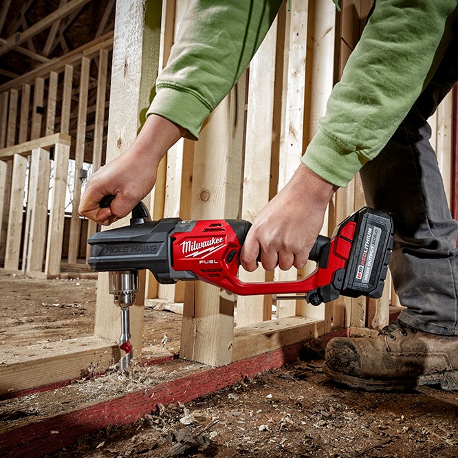 MILWAUKEE M18 FUEL Hole Hawg right angle drill in use drilling through wood framing, auger bit cutting into base plate, cordless drill with battery attached, jobsite framing application