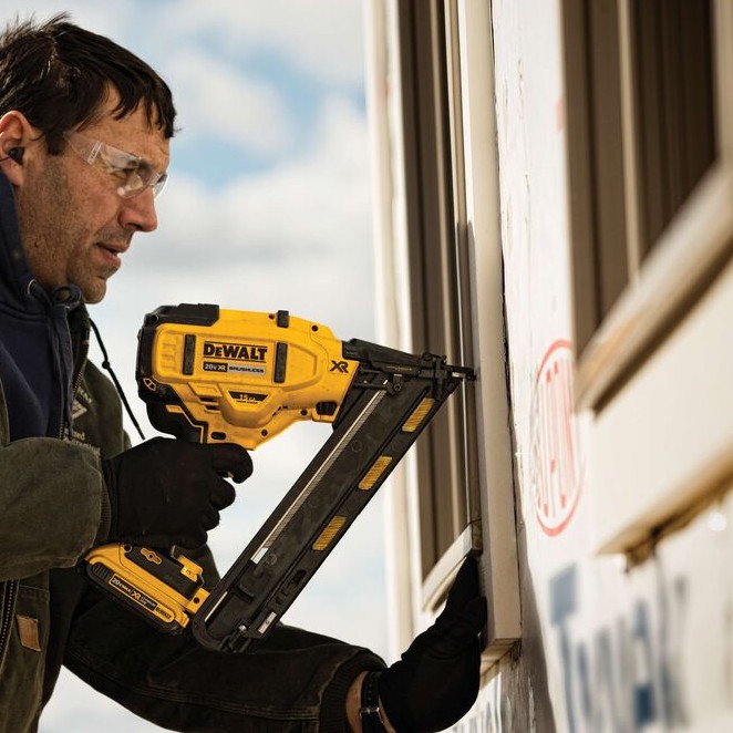 DEWALT DCN650B 20V MAX XR 15 gauge angled finish nailer installing exterior trim, contractor fastening siding trim with cordless angled nailer, battery attached, close-up side view showing magazine and nose placement