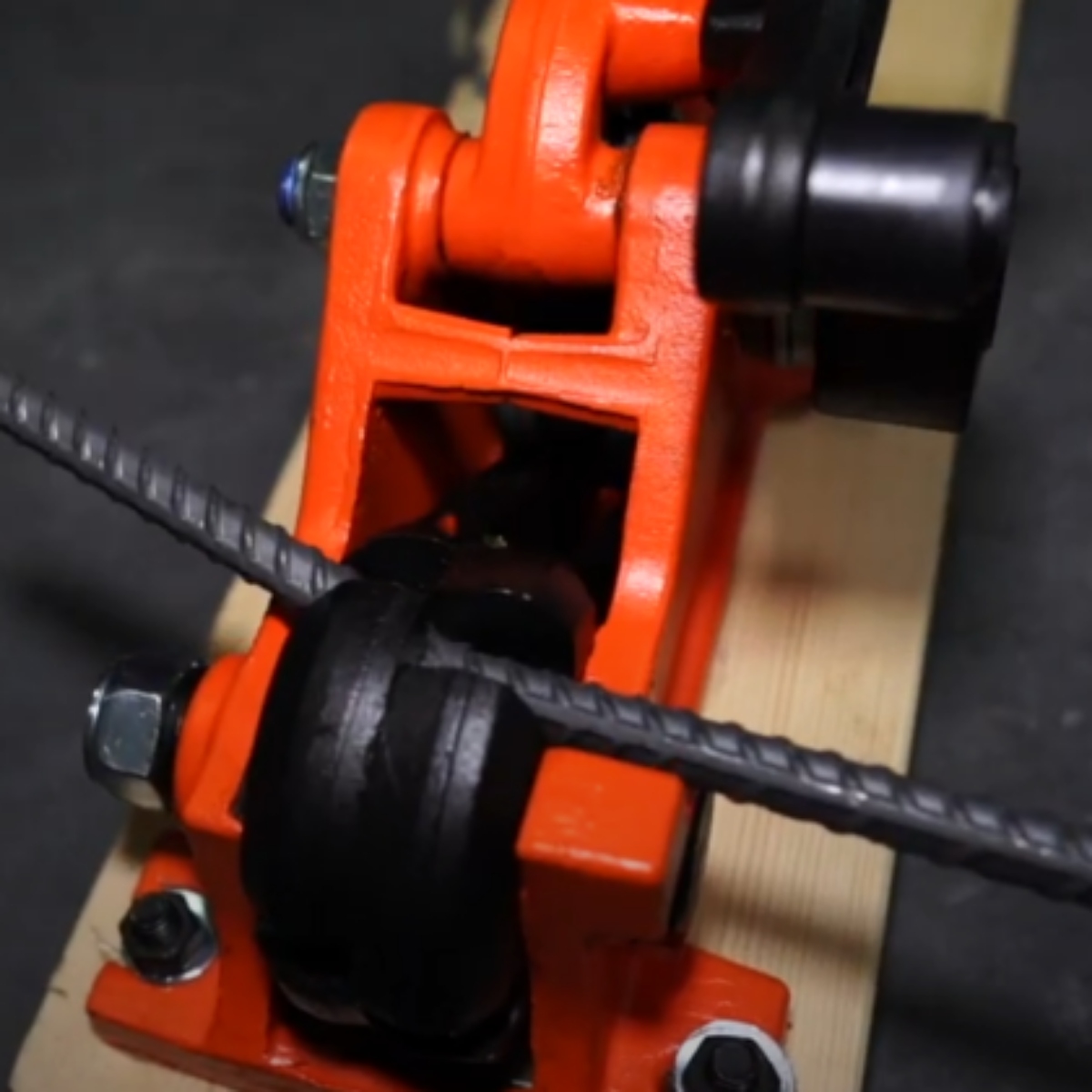 BN MBC-16B1 manual rebar bender cutter close-up showing rebar being cut between cutting jaws with blade engaged and bending rollers visible on mounted base