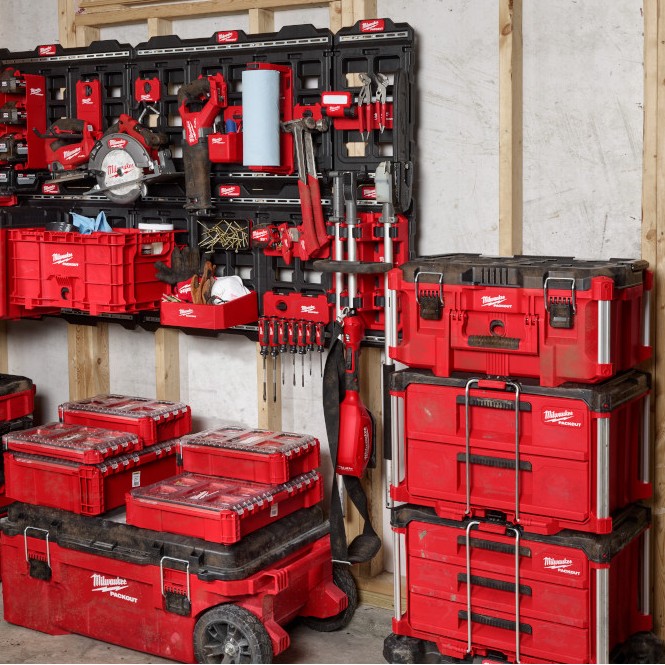 Milwaukee PACKOUT wall storage system installed in workshop with mounted tools, accessories, and stacked toolboxes for organized storage