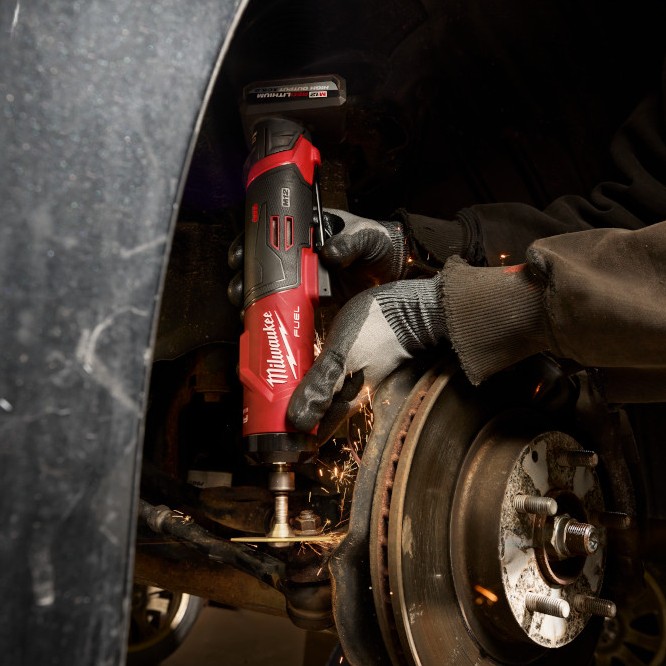 Milwaukee M12™ FUEL™ 1/4" Straight Die Grinder removing rust from an automotive suspension component, demonstrating compact cordless performance for grinding and surface preparation in tight spaces.