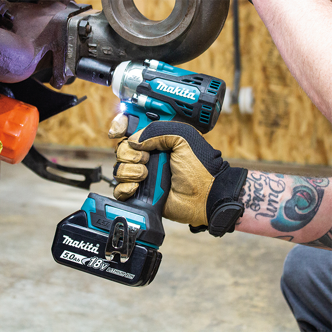 Makita DTW300XVZ 18V LXT Brushless 1/2" Impact Wrench removing heavy-duty fasteners on industrial equipment, showing compact cordless impact wrench with LED work light for maintenance, fabrication, and repair applications.