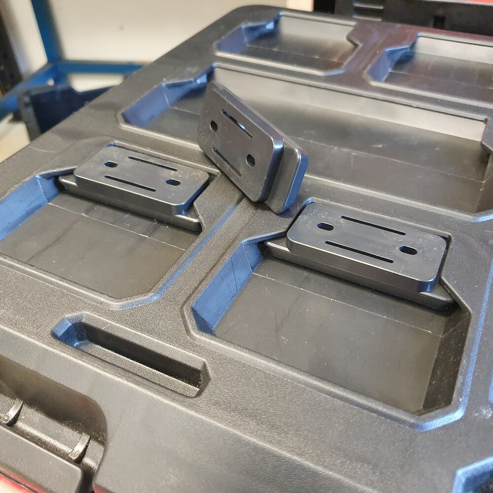Black PACKOUT™-compatible mounting feet installed on a Milwaukee PACKOUT™ lid showing fitment and mounting position