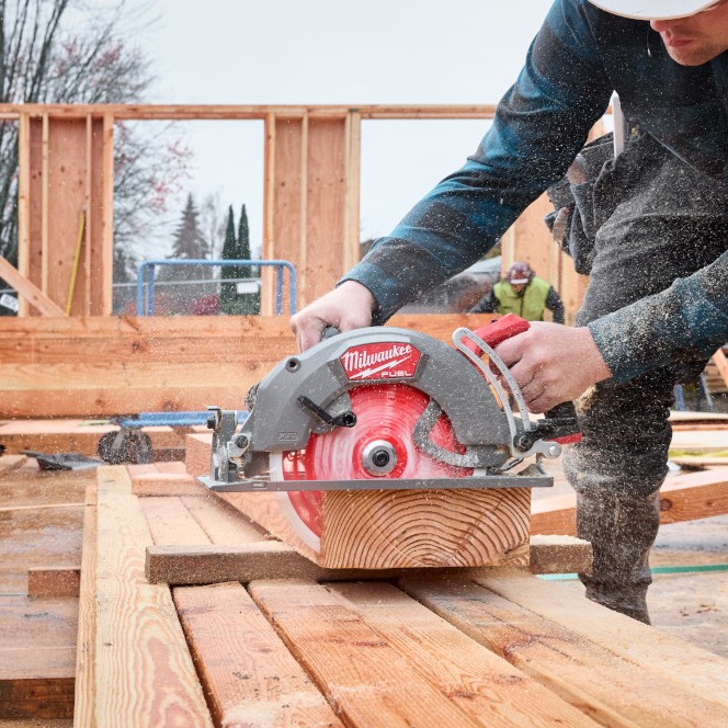 Carpenter using a Milwaukee M18 FUEL 10-1/4" rear-handle circular saw to cut a large timber beam on a framing jobsite.