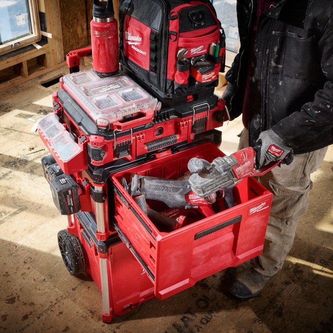 MILWAUKEE PACKOUT Single-Drawer Tool Box shown installed in a mobile PACKOUT stack on a construction site, with the drawer open for quick access to cordless power tools.
