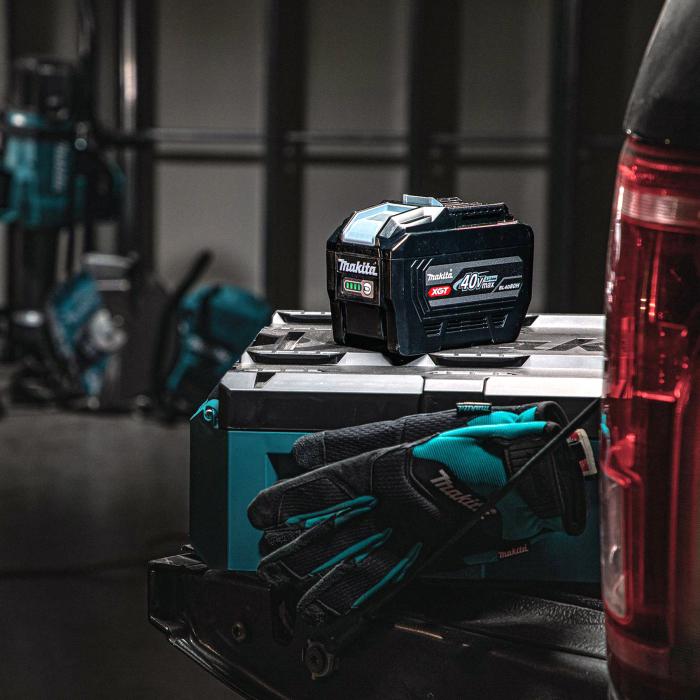 Makita BL4080H 40Vmax XGT 8.0Ah High Power Battery shown on a Makita tool case beside work gloves in the back of a service vehicle.