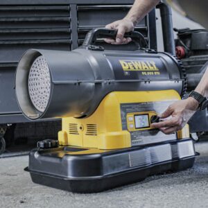 Worker adjusting the thermostat on a DEWALT 90,000 BTU cordless forced air kerosene heater, with digital temperature display visible.